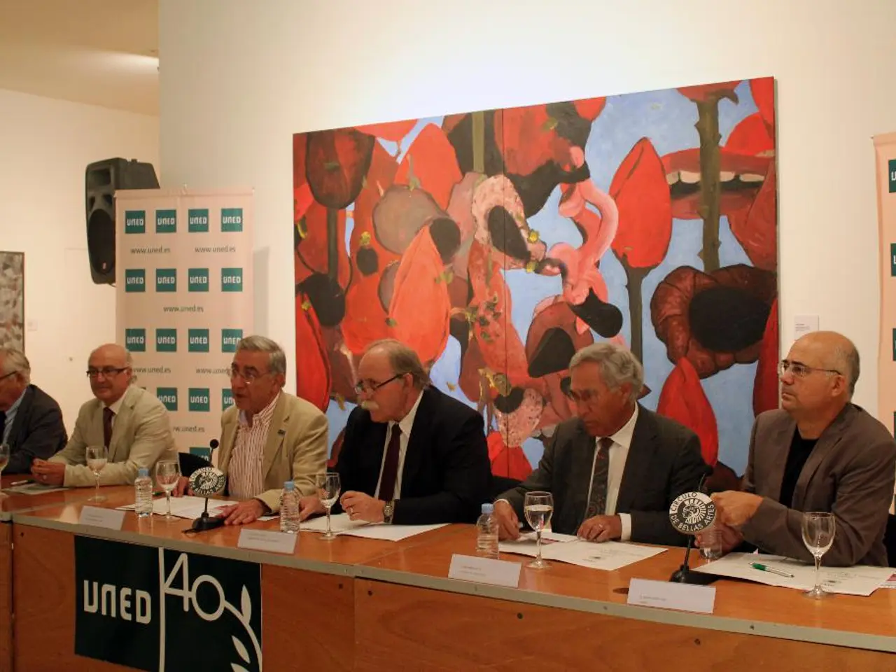 This is an inside view. Here I can see few men wearing suits, sitting on the chairs in front of the...