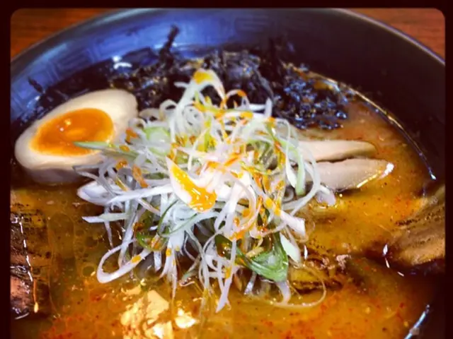 In this picture there is a food with egg in the black pan, which is placed on the wooden table top.