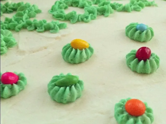 In this image there cream color base. There are flowers with cream in green color. There are...