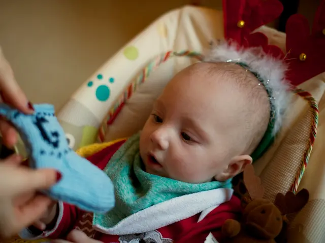 In the picture we can see a baby lying on the small bed and on the baby we can see some person...